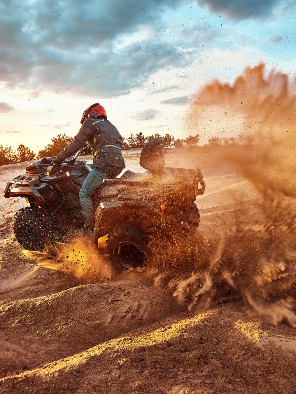 Cross-country quad bike race, extreme sports Teen riding ATV in sand dunes making a turn in the sand
